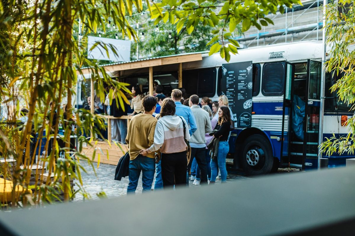Gäste stehen am Abend zwischen Lichterketten und Bambus vor dem BAM! Foodtruck an